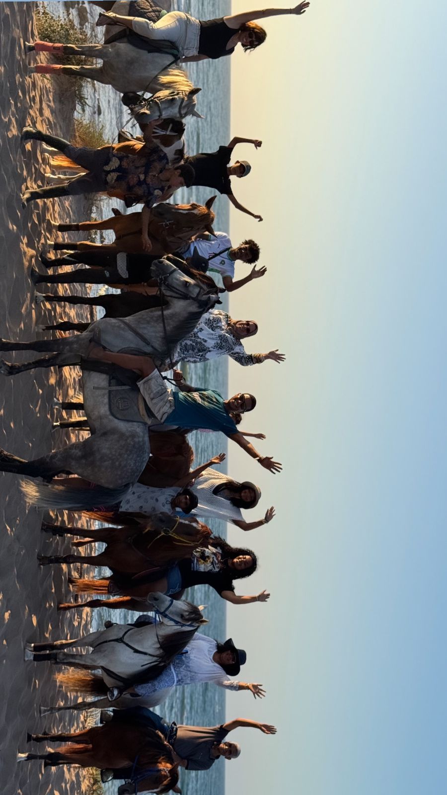 Groupe à cheval sur la plage au coucher du soleil